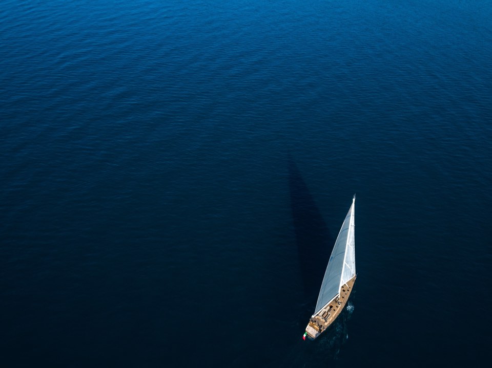 Small sailing yacht alone in a vast blue sea